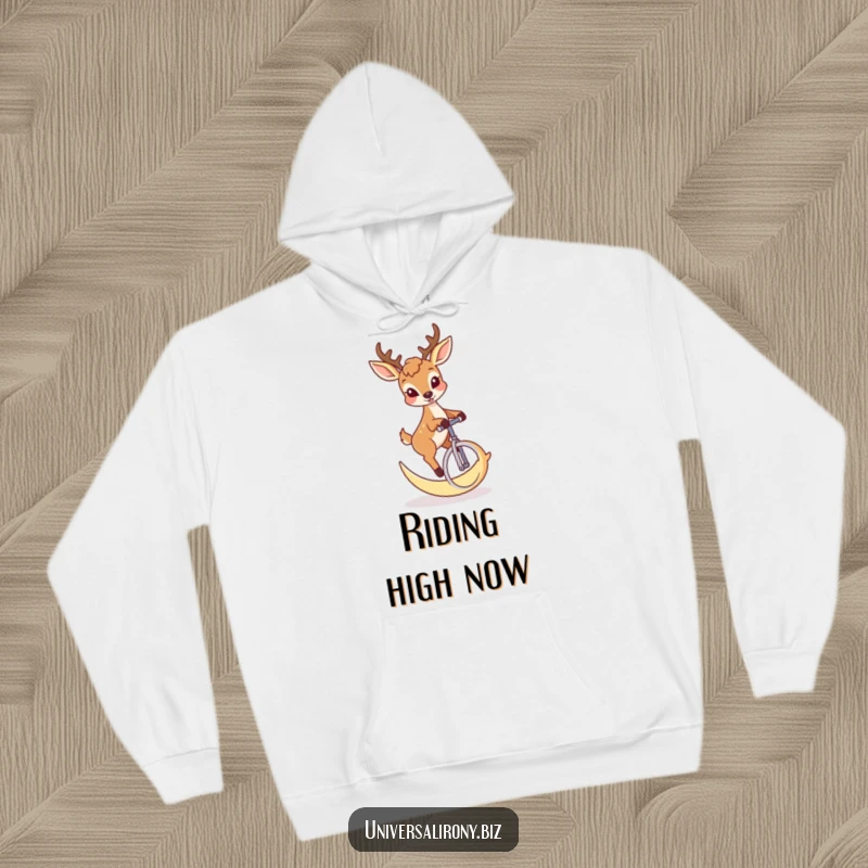 Cozy hoodie featuring a funny mischievous deer riding a unicycle made from a crescent moon.
