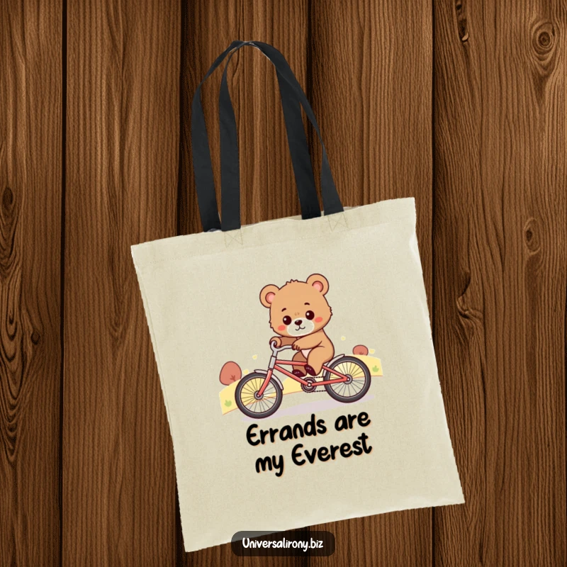 Funny tote bag featuring a determined bear cub comically riding a tiny bicycle uphill, symbolizing effort and a strong will.